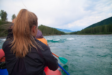 Tourists sail in a boat along a mountain river.