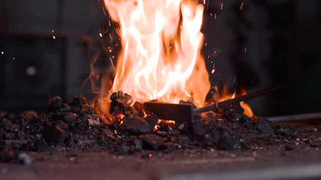 Unrecognizable blacksmith lighting coal forge fire