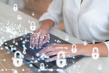 A woman programmer is typing a code on computer to protect a cyber security from hacker attacks and save clients confidential data. Padlock Hologram icons over the typing hands. Formal wear.