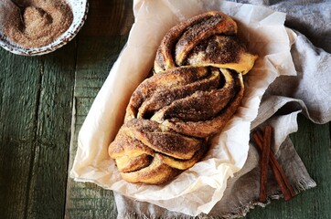 Cinnamon twisted loaf bread or babka on a dark wooden background, still life, rustic style