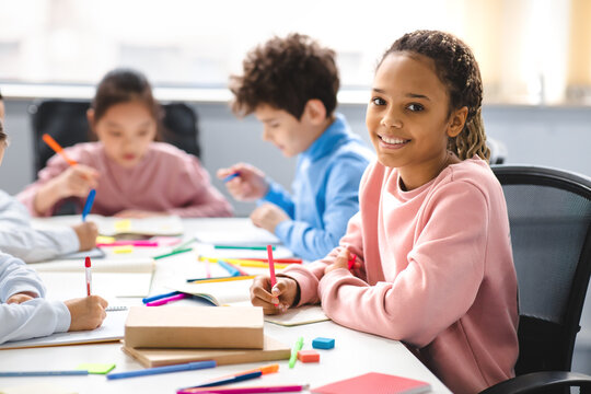 Smiling african american school girl sitting at desk in classroom