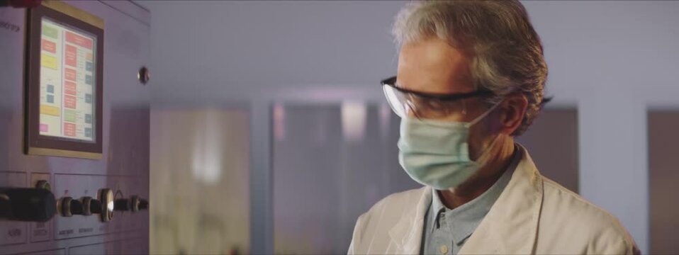 Video Of A Male Scientist Looking At Fermentation Monitor In A Milk Factory. Scientist Wearing Protective Mask And Glassses. Male Scientist Checking Fermentation Process. Factory Concept.