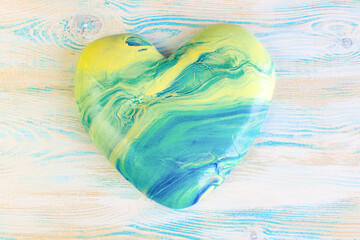 Heart from yellow-blue slime, on a wooden background. A funny antistress toy for children. Love and valentine's day concept.