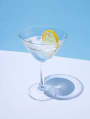 Summer stationery still life scene made with glass, dried lemon, drink, and trend palm shadow on blue pastel background. Summer vacation refreshment concept. Long shadow and refraction pattern.