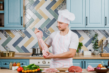 A male chef holds rabbit meat in the kitchen. The concept of cooking