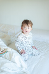 Fototapeta premium Little girl playing in pajamas in bed