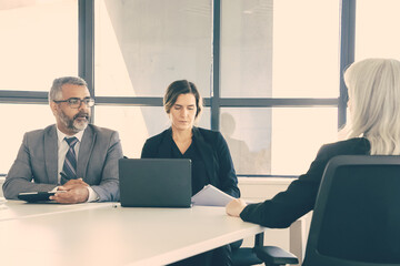 Serious company managers talking to job candidate at interview. Back view, copy space. Employment and career concept