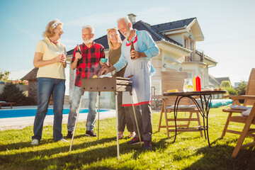 Senior friends having backyard barbecue party