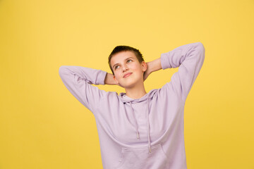 Resting, dreaming. Caucasian girl's portrait isolated on yellow background with copyspace. Beautiful female model in hoodie. Concept of human emotions, facial expression, sales, ad, fashion.