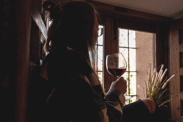 Fototapeta na wymiar Relaxed woman at the window with glass of wine