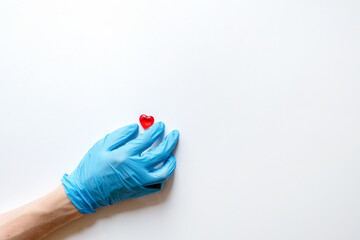 The hands of a doctor in medical gloves on a white background holding stones in the form of a heart. The concept of a healthy heart.