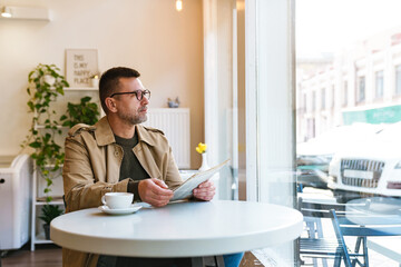 Handsome businessman reading newspaper in cafe