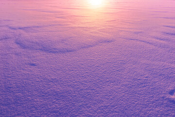 beautiful blue and purple colored snow field surface illuminated by evening sunset , violet snow texture , original winter background