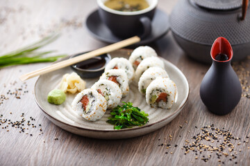 Sushi maki rolls Philadelphia with salmon, creamy cheese and avocado on a plate with chopsticks, soy sauce, wasabi and ginger. Japanese traditional seafood served for lunch in modern restaurant