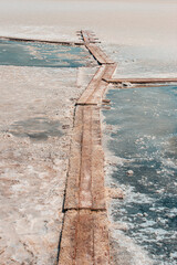 Closeup of salt layers on the shores of a pink salt lake. Old wooden way. Pedestrian wooden footbridge.