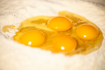 (Selective focus) Close-up view of a heap of flour with some fresh eggs inside. Flat lay, Ingredients for a homemade dough such as pasta, bakery, cakes etc.