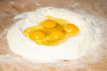 (Selective focus) Close-up view of a heap of flour with some fresh eggs inside. Flat lay, Ingredients for a homemade dough such as pasta, bakery, cakes etc.