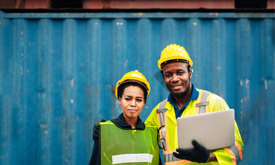 workers team man and woman smilling in safety jumpsuit with yellow hardhat and use laptop check container at cargo warehouse. transportation import,export logistic industrial good Success