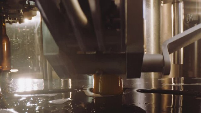 Close-up video of beer bottles capping process. Modern machine closing full glass beer bottles. Factory, brewery concept.