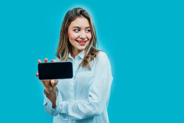 Close up photo of an attractive girl on a blue background in the studio, she is holding a phone with a black screen. Online shopping. Internet. Photo for advertising
