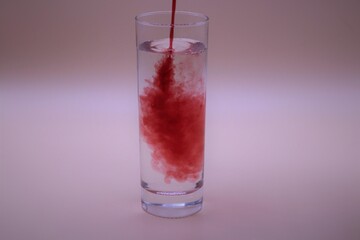 Red liquid being poured into a glass of water