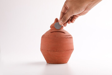 putting a coin into a clay money box: investments, retirement fund and banking concept
