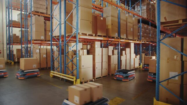 Future Technology: Automated Modern Retail Warehouse Delivery AGV Robots Transporting Cardboard Boxes in Distribution Logistics Center. Automated Guided Vehicles Delivering Goods, Products, Packages