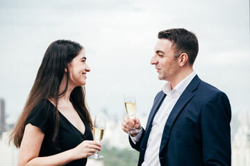 Business man and woman talking and drinking champagne celebrating success project. people meeting and greeting after work with colleague or partnership. city view background