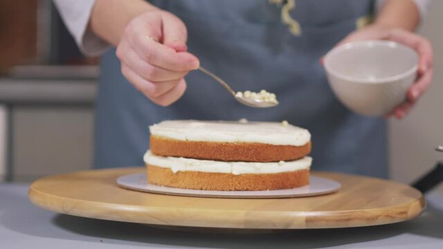 The pastry chef collects the cake, and between the layers of the sponge cake adds white chocolate balls to the cream. High quality 4k footage