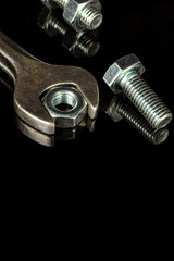 Wrench with nut and bolt on black background. The idea of connecting spare parts in construction