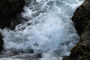 waves crashing on rocks. beautiful view of the mediterranean sea. Big stones on the beach, with water and cloudy sky background. water flowing over rocks