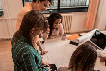 Group of women working together discussing architectural designs in the creative office.
