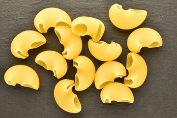 Bright yellow Pipe rigate pasta on a slate board, close-up, top view.