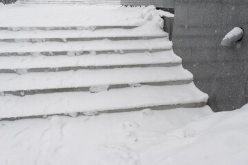 the steps of the street stone stairs are covered with snow.