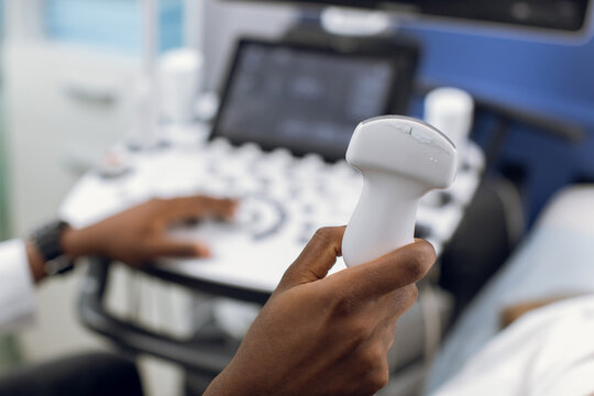 Close up photo of ultrasound scanner in the hands of male African American doctor. Diagnostics. Sonography. Modern ultrasound machine on the blurred background