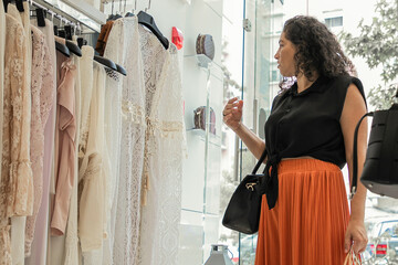 Excited female customer staring at dress on rack in fashion store. Low angle, candid shot. Boutique or retail concept
