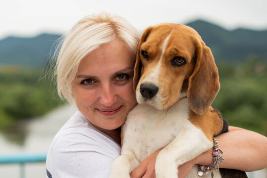 Cute Woman Close Up Portrait, Hugging Beagle Dog At The Walk. Smiling Young Woman Enjoying Good Day And Posing With Pet. Real People Concept.