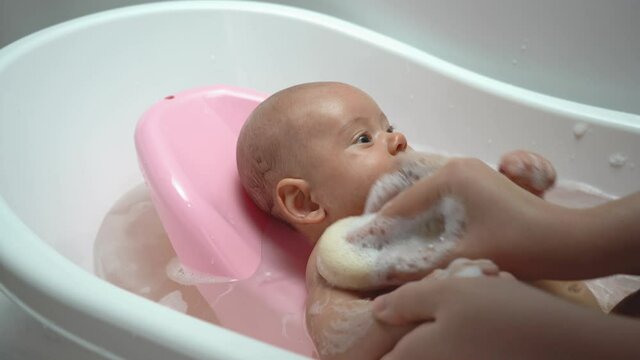 Mother washes the armpit of a newborn with a sponge