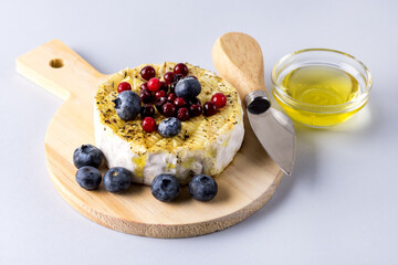 Baked or Fried Grilled Camembert or Brie Cheese with Berry and Honey on Small Wooden Tray Gourmet Breakfast Blue Background Cheese Knife