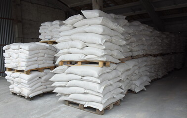 Bags of flour and grain are stacked on pallets, stored in the factory warehouse. Ready-made...