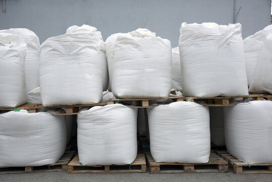 Large bags of grain and flour are stored in an industrial warehouse, ready for further transportation and processing.