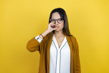 Young beautiful woman wearing a blazer over isolated yellow background with mouth and lips shut as zip with fingers. Secret and silent, taboo talking