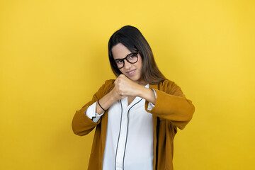 Young beautiful woman wearing a blazer over isolated yellow background Punching fist to fight, aggressive and angry attack, threat and violence