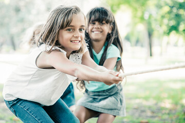 Team of happy kids pulling rope, playing tug-of-war, enjoying outdoor activities. Group of children...