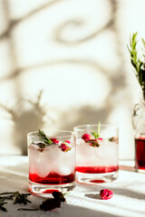 Refreshing rose liqueur with rosemary. The front glass in focus.