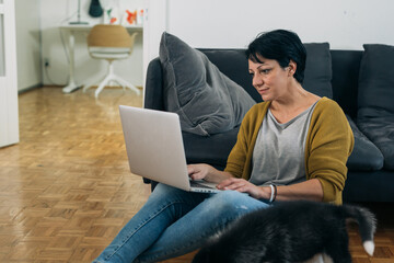 woman sitting on the floor in her living room and using laptop computer