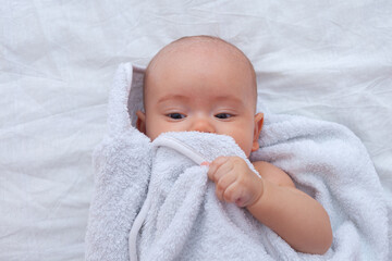 Newborn after bathing in the bathroom wrapped in a white towel