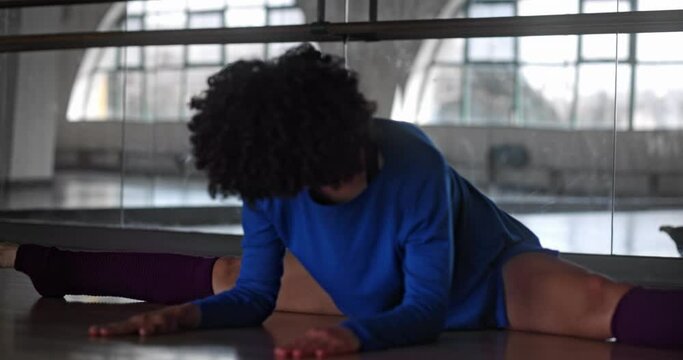 African-american woman doing leg split on dance studio