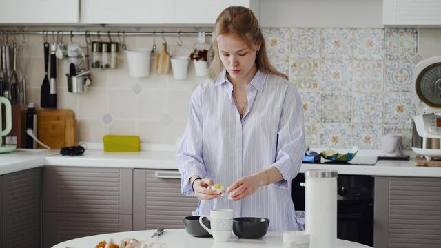 A girl with a problem skin breaks an egg with a knife. Separates the white from the yolk.
