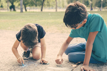 Focused boys sitting and drawing with colorful chalks. Childhood and creativity concept